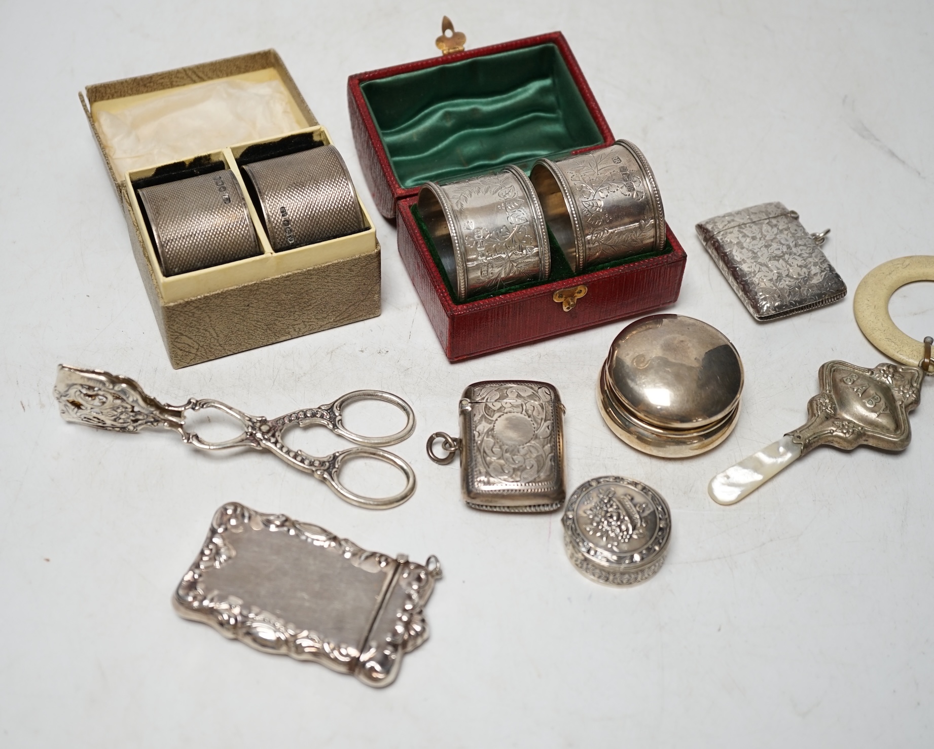 A cased pair of Edwardian engraved silver napkin rings, one other pair of engine turned silver napkin rings and sundry small items of silver, white metal and 925 including vesta cases, child's rattle, etc. Condition - po